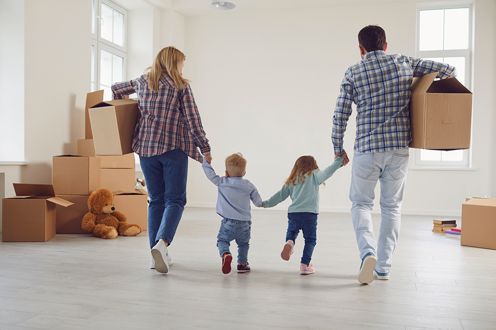 Happy family with children moving with boxes in a new apartment house. 